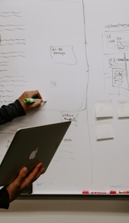 man wearing gray polo shirt beside dry-erase board