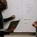 man wearing gray polo shirt beside dry-erase board