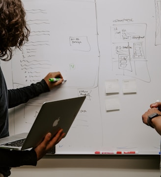 man wearing gray polo shirt beside dry-erase board