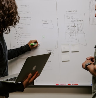 man wearing gray polo shirt beside dry-erase board