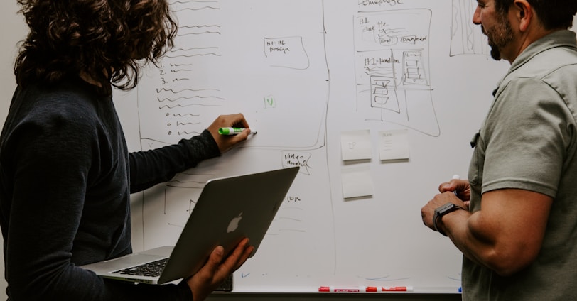 man wearing gray polo shirt beside dry-erase board