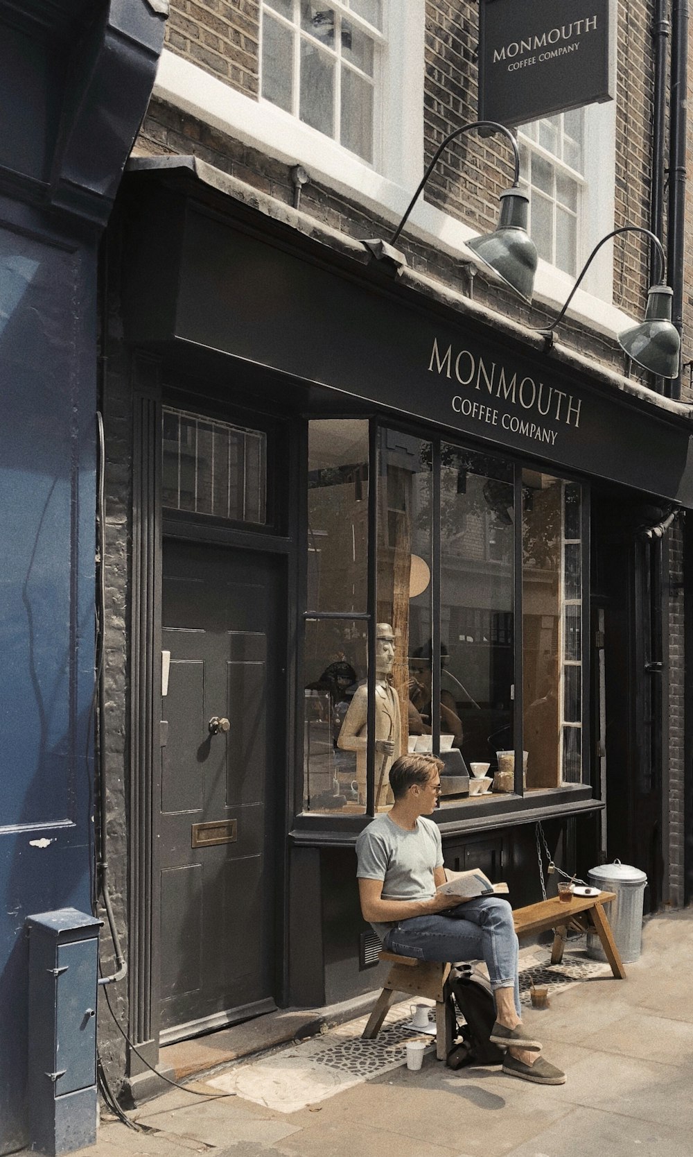 man sitting on bench in front of Monmouth store during daytime