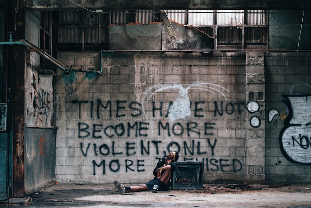 man leaning on wall with text