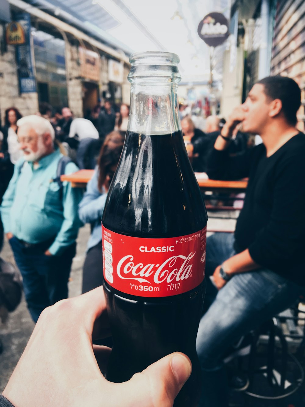person holding 350 ml clear glass Coca-Cola soda bottle