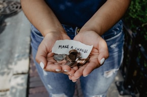 person showing both hands with make a change note and coins