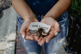 person showing both hands with make a change note and coins