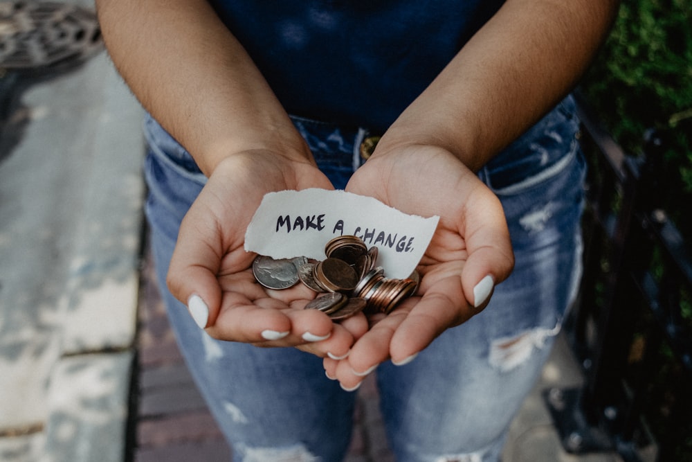 person showing both hands with make a change note and coins