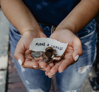 person showing both hands with make a change note and coins