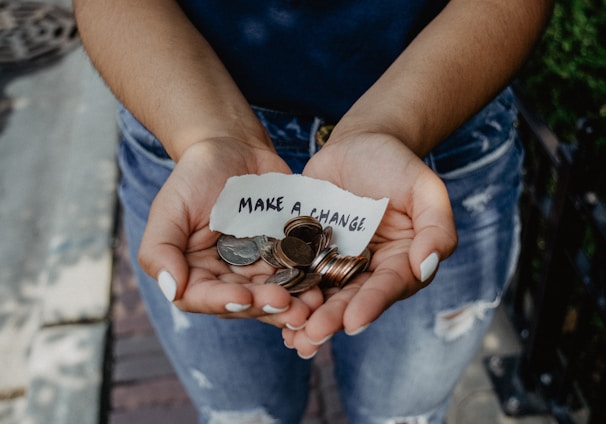 person showing both hands with make a change note and coins