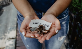 person showing both hands with make a change note and coins