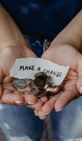 person showing both hands with make a change note and coins