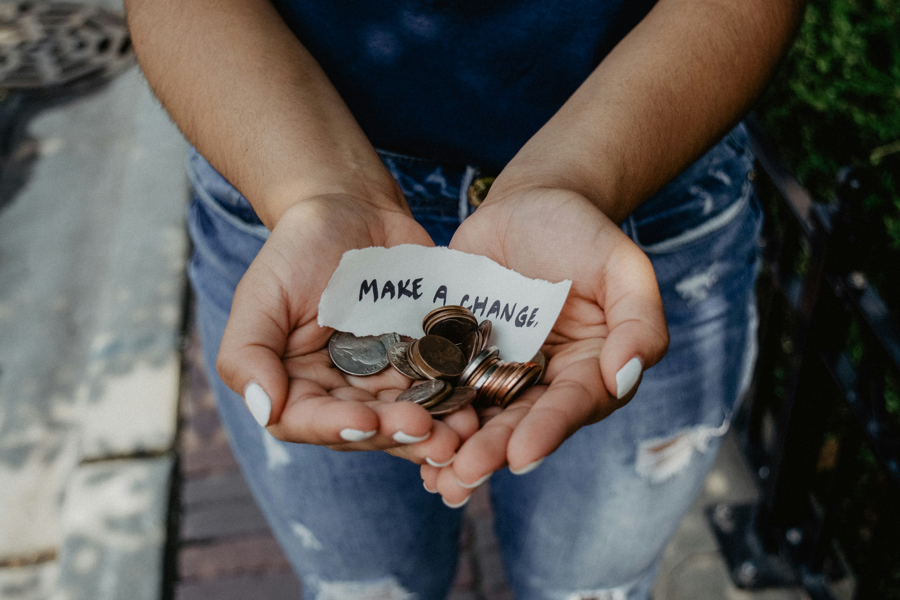 Image captured by Katt Yukawa. Woman holding coins with a slip of paper with "Make a Change" written on the slip.