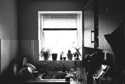 Monochrome photo of a modern kitchen with clean lines and natural light pouring through large windows.