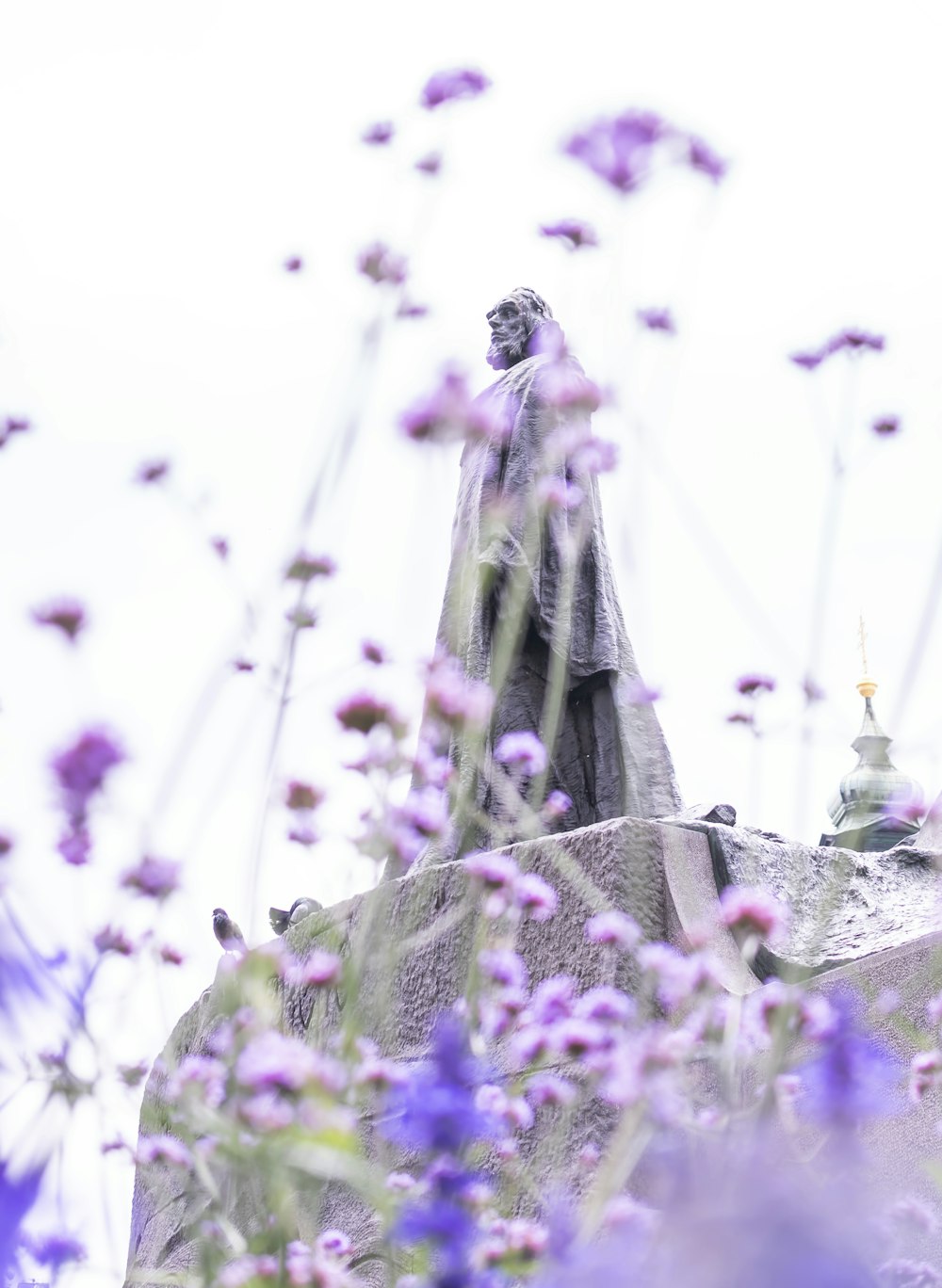 low angle photo of man wearing cloak statue under clear sky