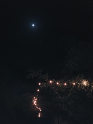 A cozy night scene featuring a person wearing a moon-themed shirt under a starry sky.