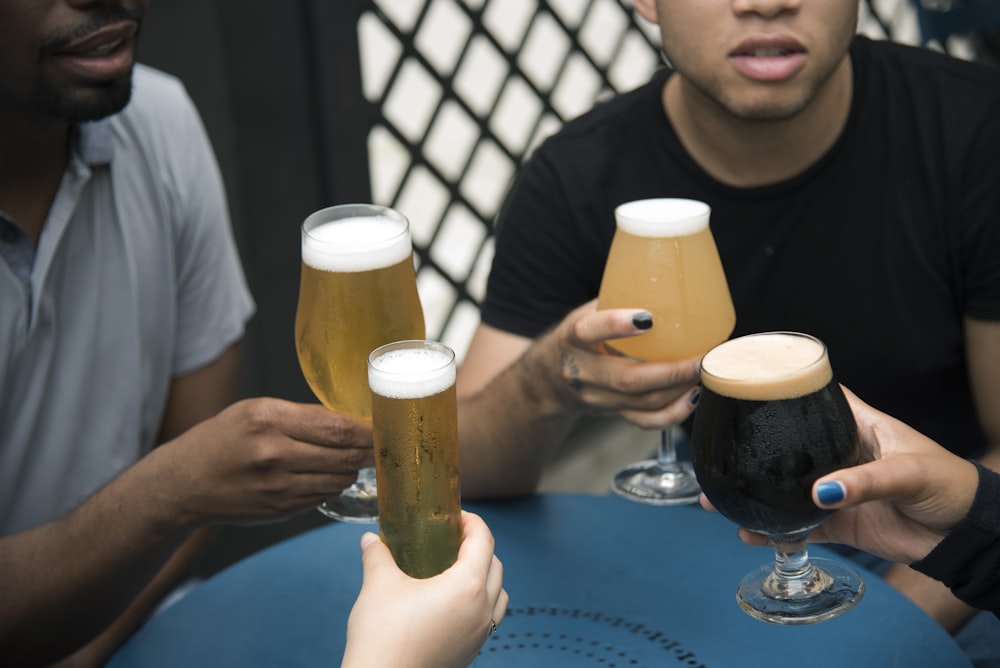 four person holding glass goblets