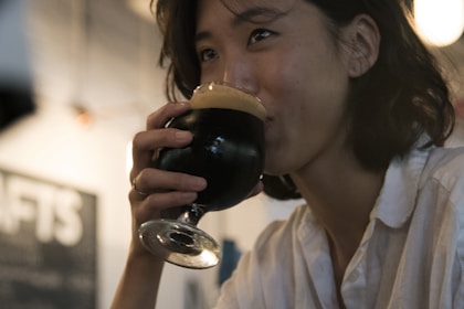 selective focus photography of woman drinking from short-stemmed glass