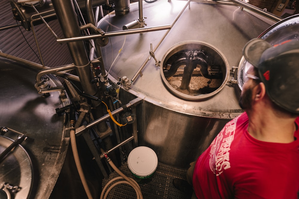 man standing beside stainless steel industrial machinery