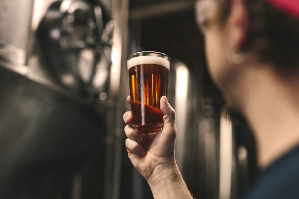 selective focus photography of person holding clear drinking glass