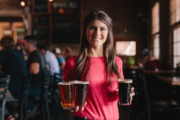 Experienced waitstaff smiling warmly as they serve drinks at a lively pub.