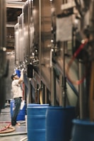 man in white crew-neck top and blue jeans standing in front of storage tank