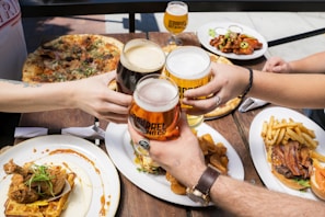 A group of friends clinking glasses over a table filled with diverse Asian fusion dishes