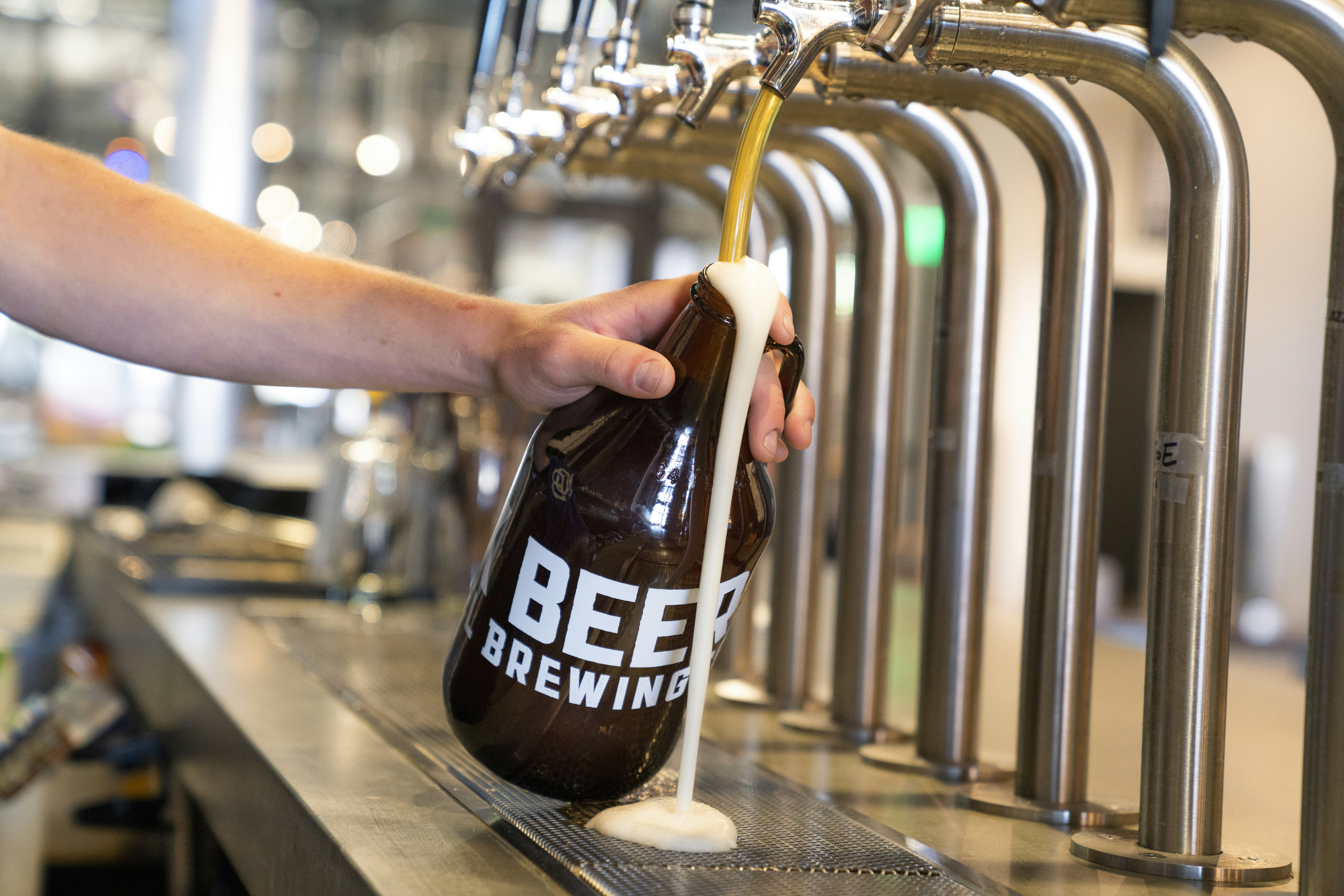 A growler being overfilled at a brew pub.