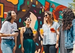 four women holding drinks while laughing together during daytime