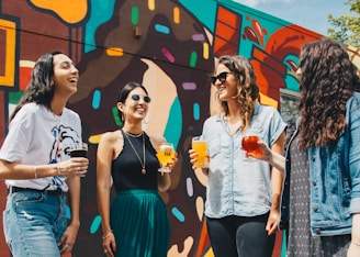 four women holding drinks while laughing together during daytime onlyfans