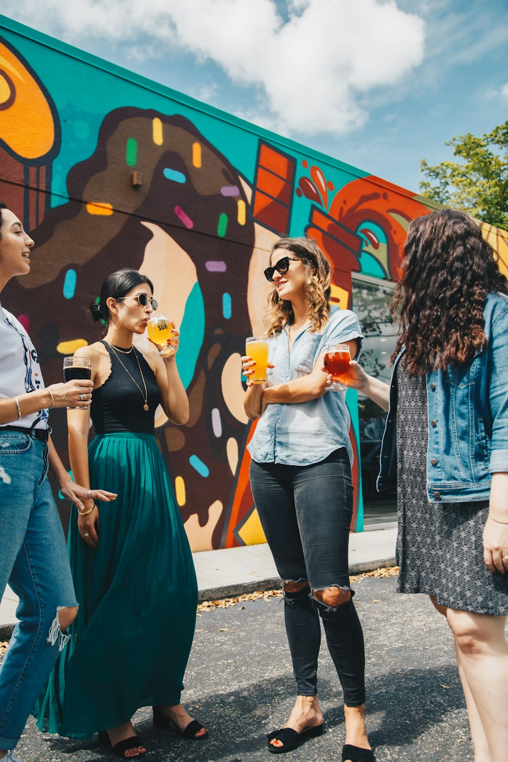 four women holding drinking cups during daytime