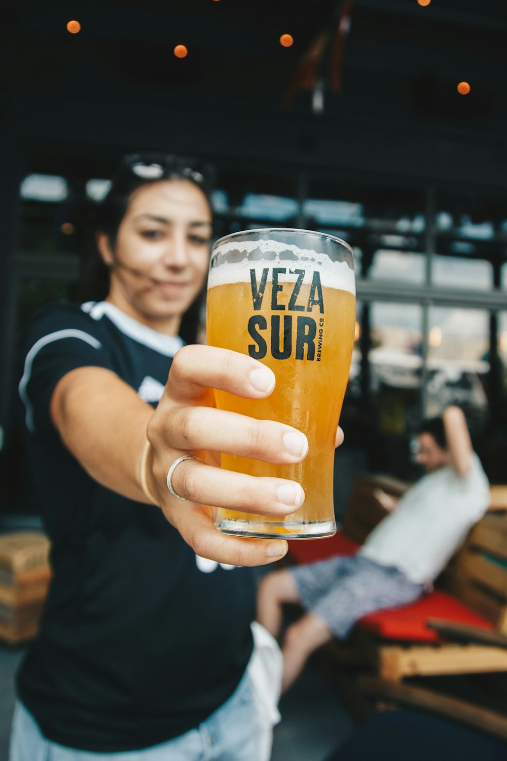 Frau mit Veza Sur Trinkglasbecher gefüllt mit Bier