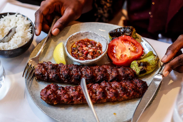 Charcoal-grilled seekh kebab skewers with chutney and rice