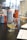 On a table, several snifter glasses partially filled with a golden liquid are placed alongside colorful beverage cans. There are some laboratory bottles in the background, and a paper with a chart or table is visible in the foreground.