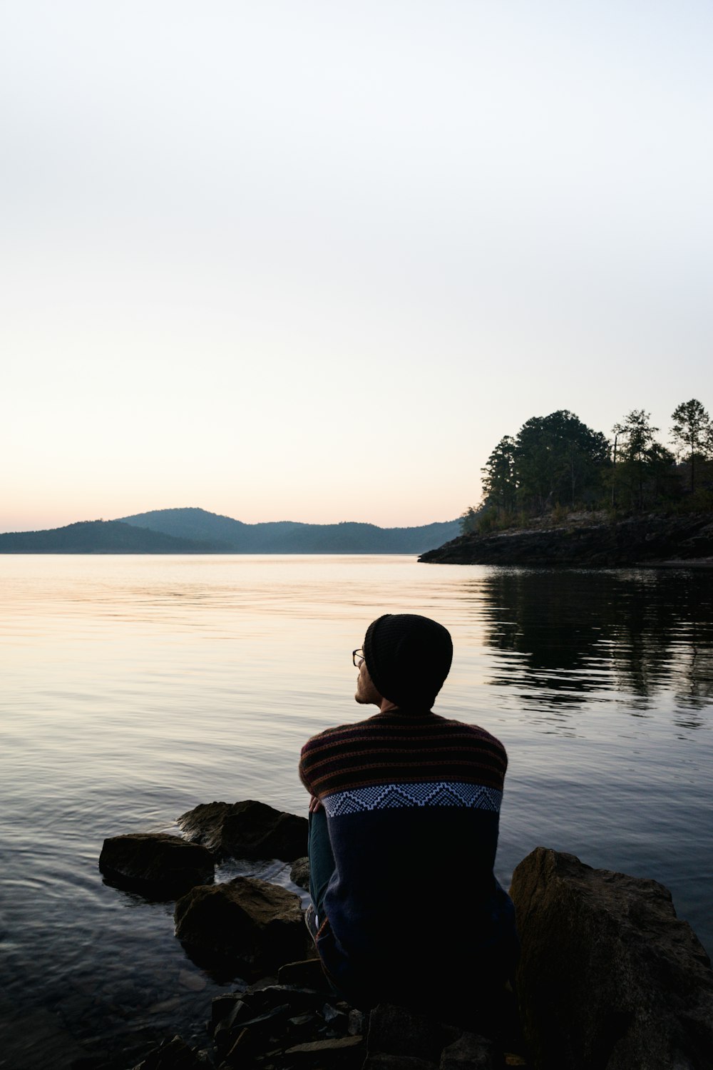 person sitting on rock near body of water