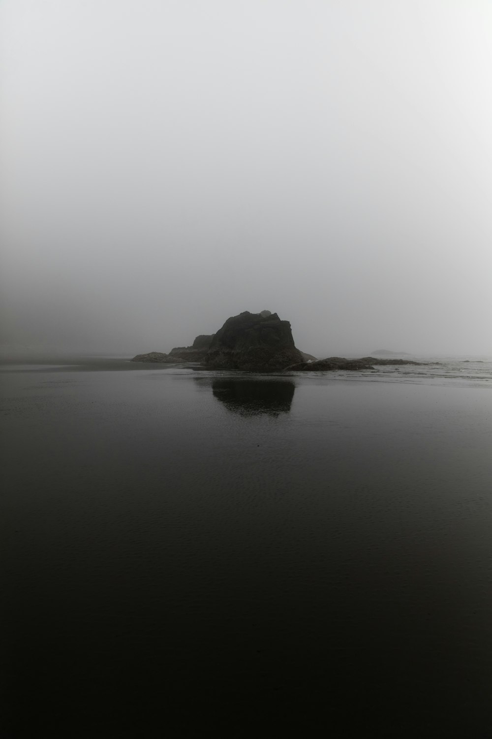 silhouette of rock formation in front of body of water