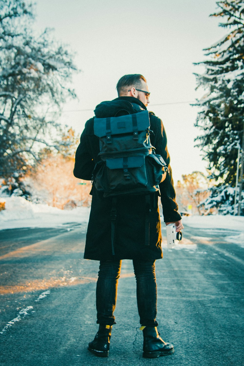 man wearing backpack in middle of the road