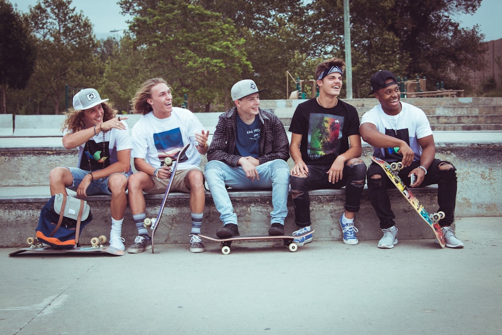 Fünf Gruppen von Männern, die zusammen mit ihren Skateboards sitzen