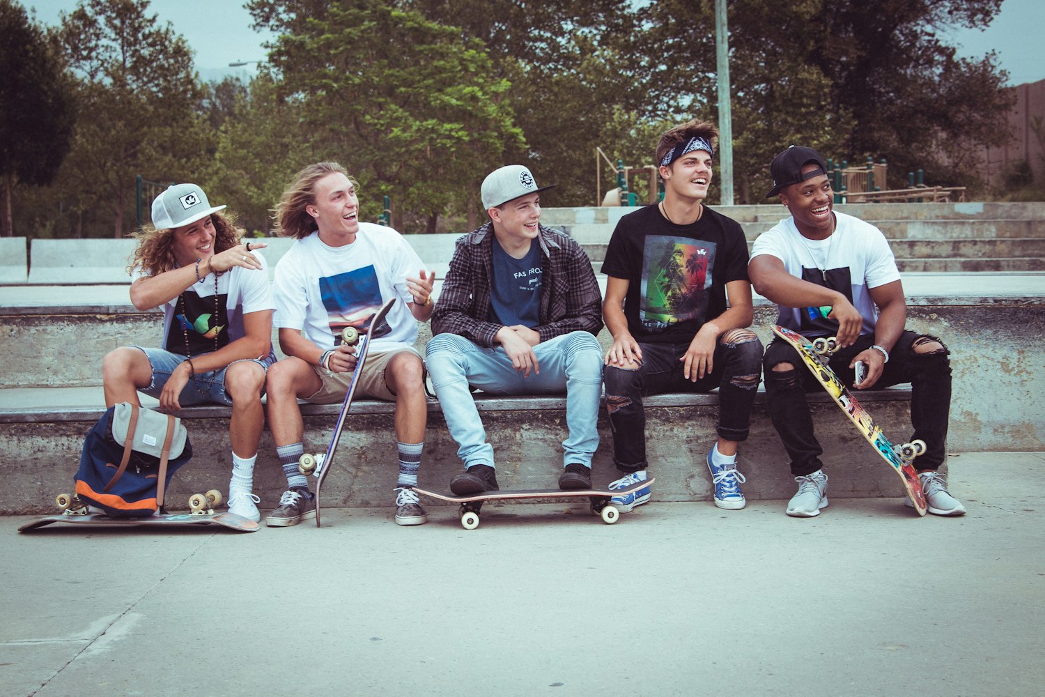 five group of men sitting together with their skateboards by Parker Gibbons