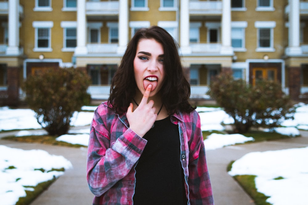 woman standing putting its finger on her tongue