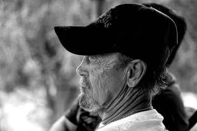 grayscale photography of man wearing black cap expressive teams background