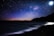 A serene night sky filled with stars and a glowing moon over a tranquil ocean.