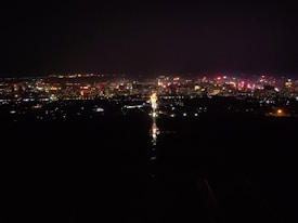 A vibrant cityscape at night, with numerous buildings illuminated by bright lights in various colors, creating a lively and dynamic skyline.