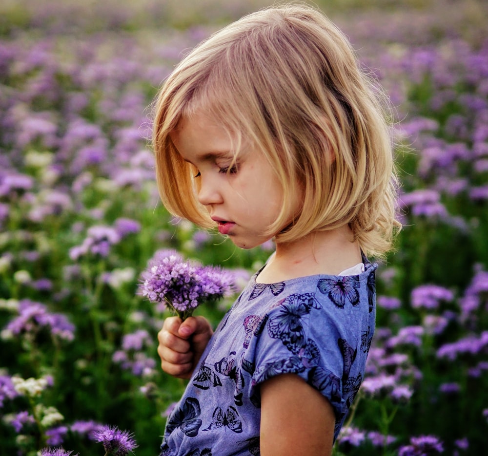 menina segurando flores roxas