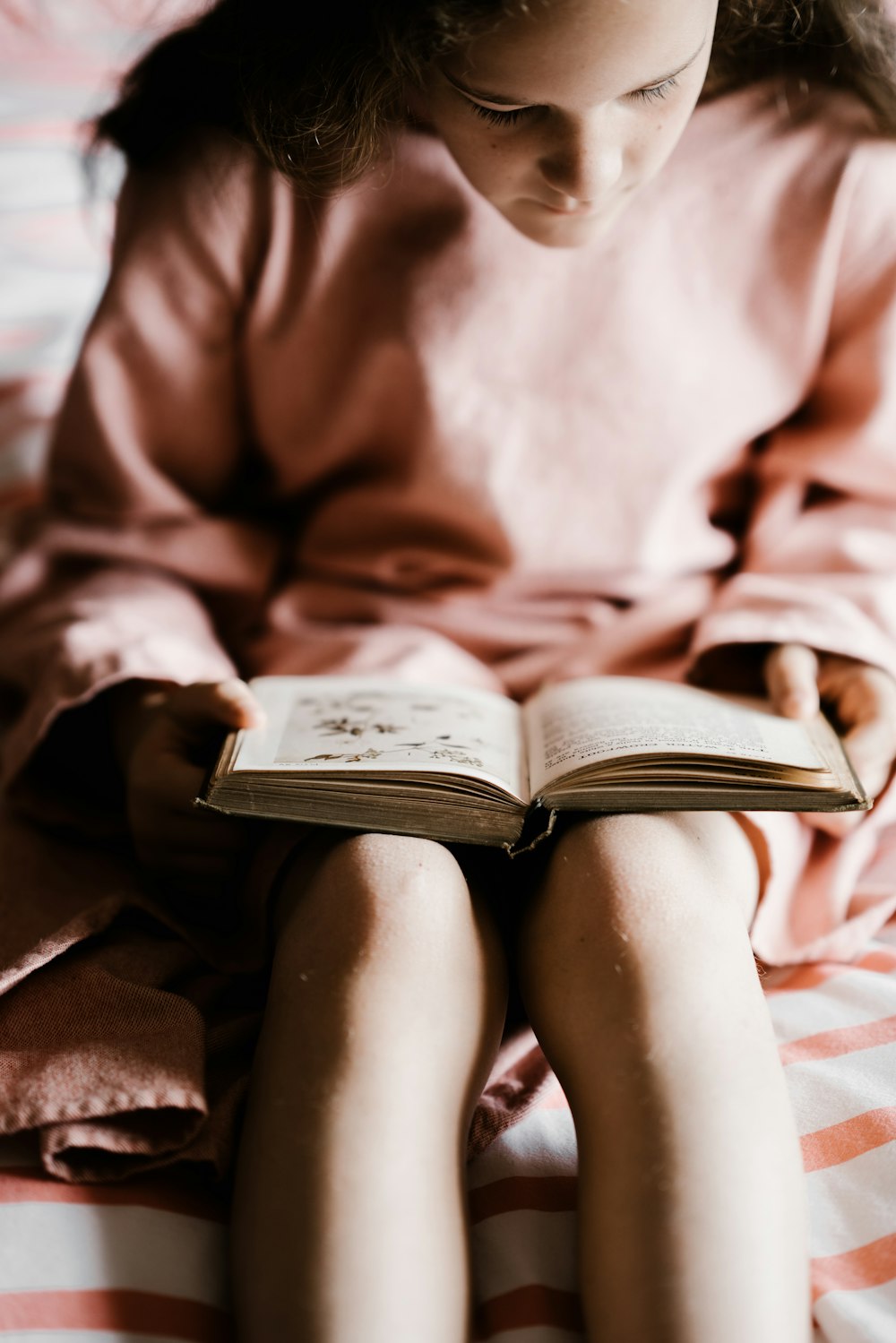 Chica en rosa de manga larga con libro de sostenimiento