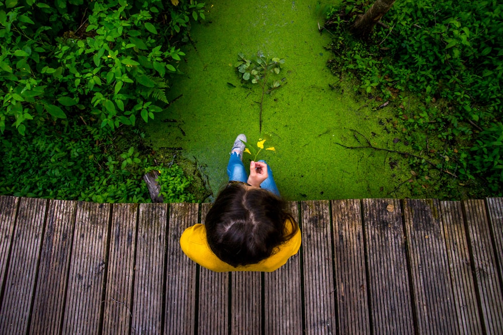 Person sitzt auf Holzbrücke