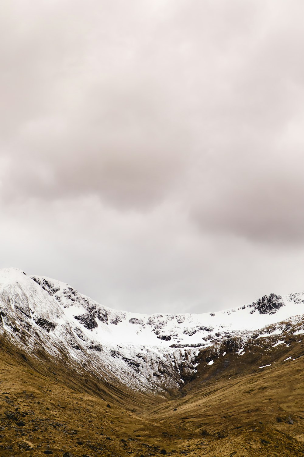 Chaîne de montagnes enneigée sous ciel nuageux