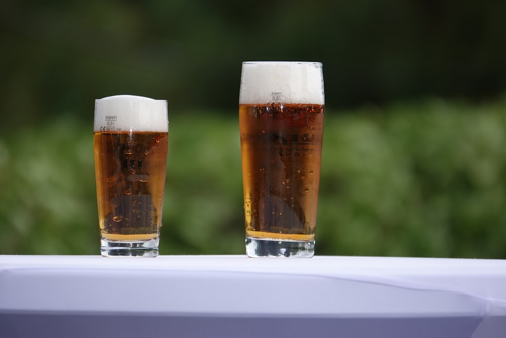 two conical clear pint glasses on white surface