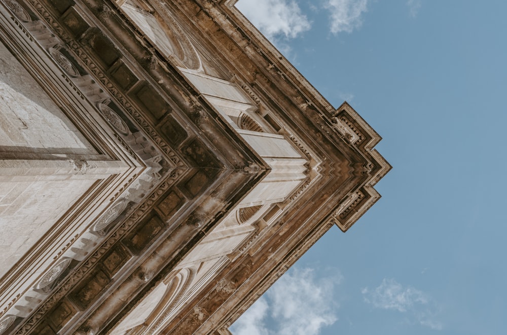 low angle photography of beige building under blue cloudy sky