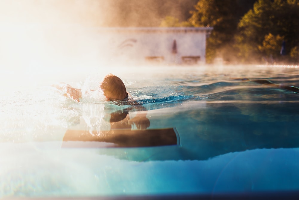 person swimming on blue water pool