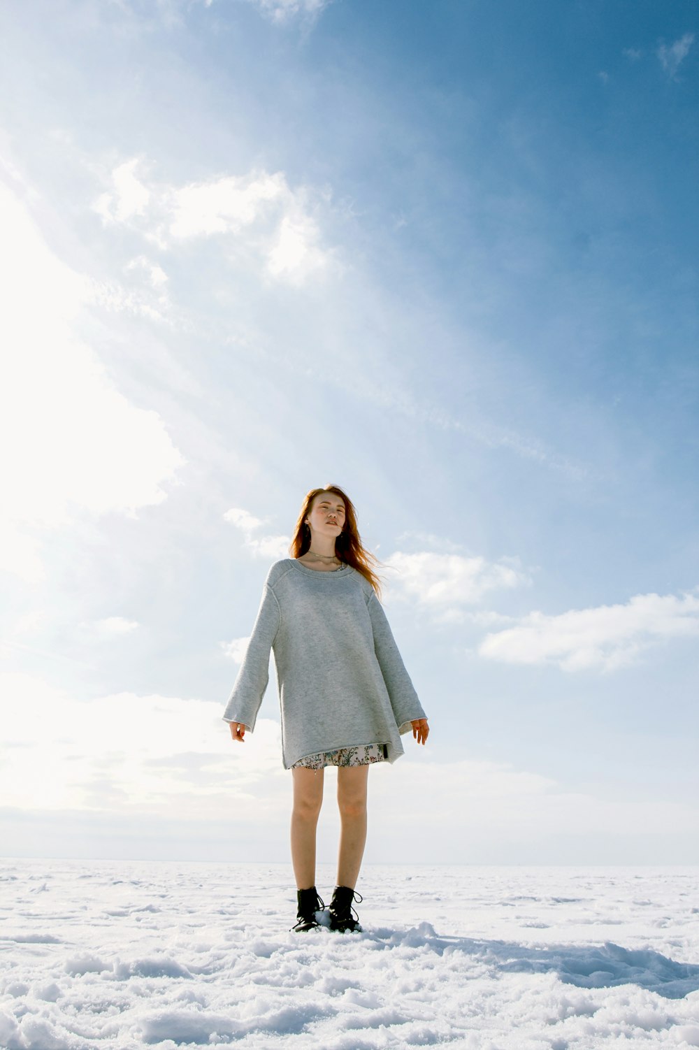 woman in gray crew-neck long-sleeved shirt standing on snowfield